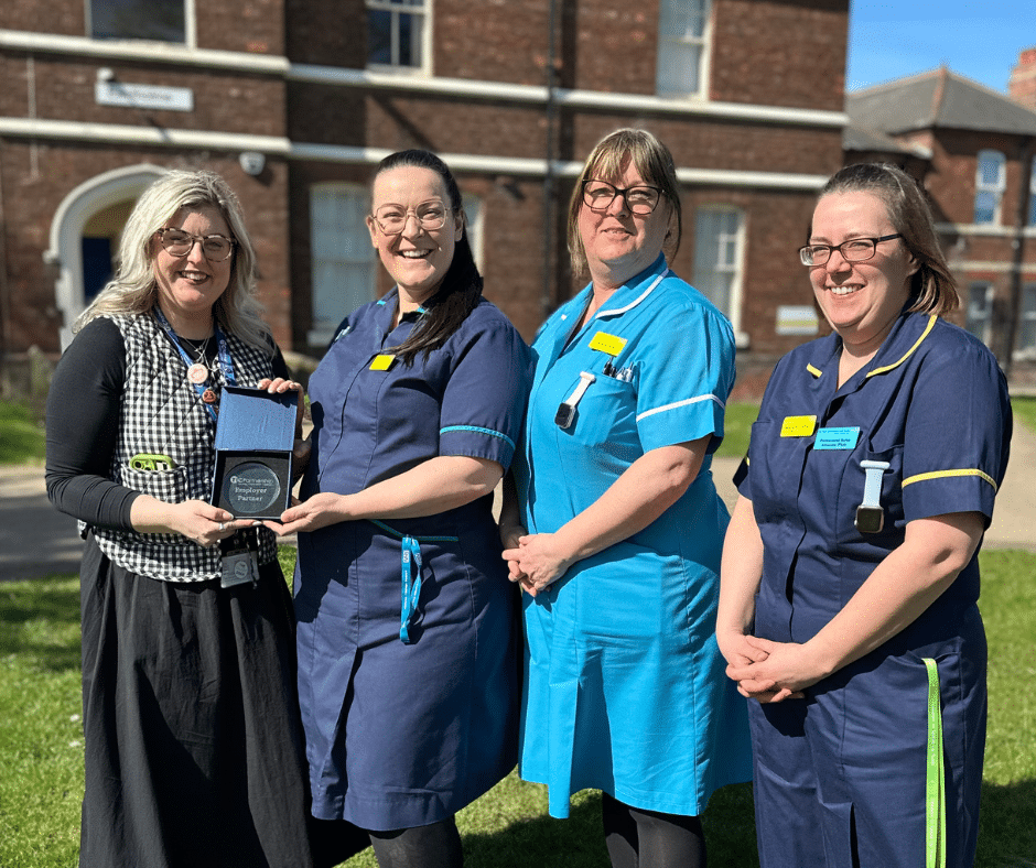 Tia Campbell from Grimsby Institute, Laura Horn and NHS staff standing holding the employer partner award.